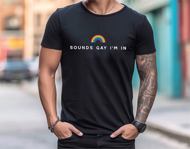 K&ouml;nnte beinhalten: Ein schwarzes T-Shirt mit einem Regenbogen-Motiv und dem Text "SOUNDS GAY I'M IN".