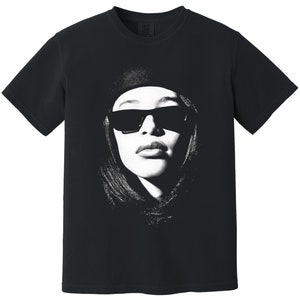 May include: Black t-shirt featuring a white graphic print of a woman wearing sunglasses and a beret.
