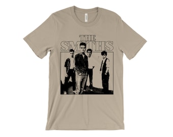 May include: A beige t-shirt with a black and white image of the band The Smiths. The band members are standing in a row and the band's name is printed in large letters above them.