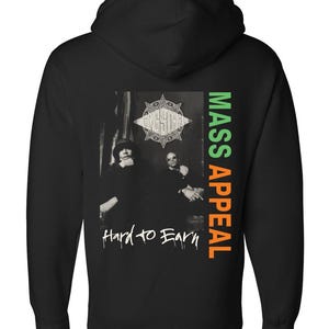 Puede incluir: Sudadera con capucha negra con un gráfico de dos personas en una foto en blanco y negro. El texto "GANG STARR" está encima de la imagen, con "MASS APPEAL" en verde y naranja a la derecha. Las palabras "Hard to Earn" están debajo.