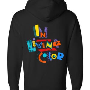 Può includere: Felpa con cappuccio nera con un design grafico colorato sul retro. Il design presenta le parole "IN LIVING COLOR" in vari colori e caratteri vivaci, tra cui giallo, blu, rosso e viola.