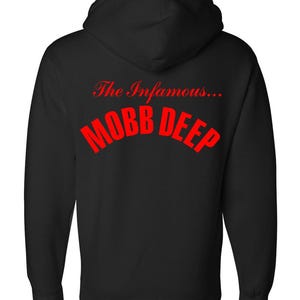 May include: Black hooded sweatshirt featuring the text "The Infamous... MOBB DEEP" in red. The hoodie has a drawstring and a kangaroo pocket. The sweatshirt is made of a soft, comfortable material.