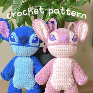 Op de afbeelding: Twee gehaakte Stitch en Angel knuffels. Stitch is blauw met een lichtblauw lichaam en Angel is roze met een wit lichaam. Beide hebben paarse ogen en oren.