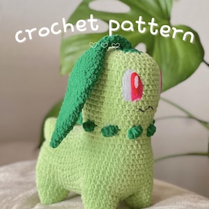 May include: A handmade crochet Chikorita plushie in shades of green, with a green leaf on its head and red and white eyes. The text "crochet pattern" is written across the top of the image.