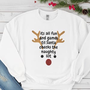Funny Christmas Sweatshirt – “It’s All Fun & Games Til Santa Checks the Naughty List” – Reindeer Red Nose Tee – Holiday Gift for Her