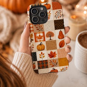 May include: A phone case featuring a patchwork design of autumn-themed squares. The pattern includes illustrations of orange pumpkins, maple leaves, bare trees, acorns, and plaid textures in shades of brown, orange, cream, and dark green.