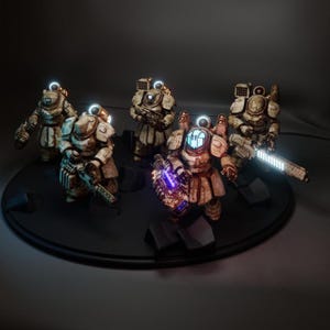 Puede incluir: Cinco figuritas de robots blancas y marrones con luces azules brillantes en sus cabezas. Los robots sostienen varias armas y están de pie sobre una base circular negra.