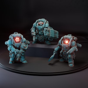 May include: Three teal miniature figures in armoured suits with glowing red eye-like features. One figure holds a weapon, another a case, and the third a weapon. The figures are on a dark surface.