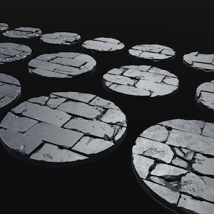 Puede incluir: Un conjunto de 14 bases redondas de textura de piedra gris para figuras en miniatura. Las bases están dispuestas en un patrón escalonado, con la base más grande en el centro.