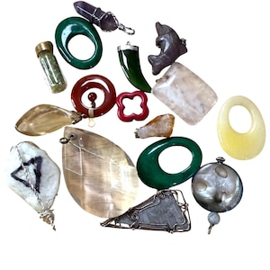 May include: A selection of gemstone pendants and charms in diverse shapes and colours. Includes green, red, yellow, and clear stones, some with silver or wire accents. A variety of jewellery pieces.