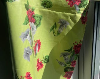 Pode incluir: Um tecido verde com um padrão floral com flores vermelhas e brancas. O tecido está drapeado sobre um peitoril de janela.