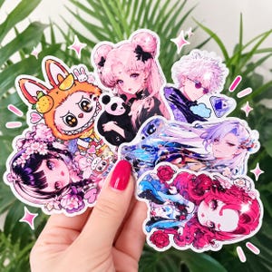 May include: A collection of die-cut vinyl stickers featuring various anime-style characters, including a figure with pink hair holding a panda, a character in an orange rabbit costume, and others with vibrant hair colors and floral accents.