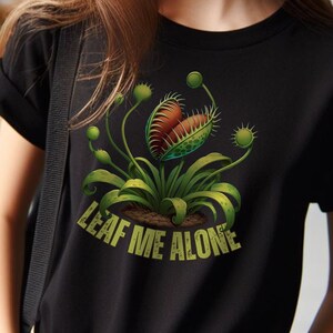 May include: Black t-shirt with a green Venus flytrap graphic and the text "LEAF ME ALONE".