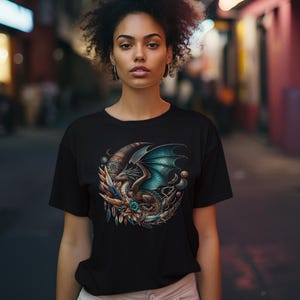 This image features a woman in a black t-shirt that has a vivid brown & turquoise dragon with dark boho style moon, feathers and accessories. It also has color choices and printing info on the image.