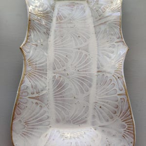 May include: White ceramic serving tray with a scalloped edge and a delicate fan pattern. The tray has a subtle gold rim.