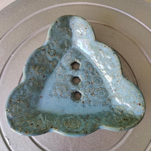 Könnte beinhalten: Eine hellblaue Keramik-Seifenschale mit floralem Muster und drei Abflusslöchern. Die Schale ist in Form einer Wolke.