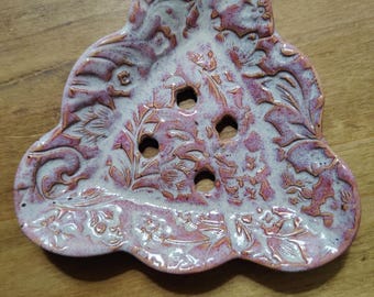 May include: A pink and white ceramic soap dish with a floral design and drainage holes.