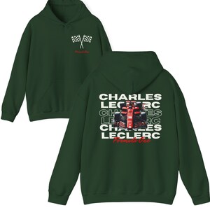 May include: A dark green hoodie with a white graphic of a Formula One race car and the text "CHARLES LECLERC Formula One" on the back. The front of the hoodie has a small white graphic of a checkered flag.