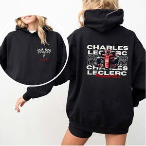 May include: Black hoodie with a white checkered flag graphic on the front and a red Formula One race car graphic with the text "CHARLES LECLERC Formula One" on the back.