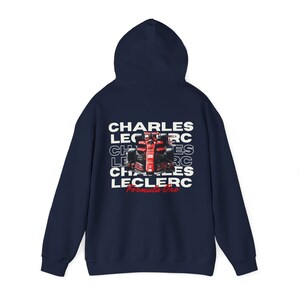 May include: Navy blue hooded sweatshirt with a white graphic of a Formula One race car and the text "CHARLES LECLERC Formula One" repeated multiple times.