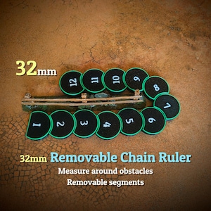 May include: A 32mm removable chain ruler consisting of twelve black circular segments with green edges, each numbered 1 through 12 in white. The segments are arranged in a curved line next to a brown wooden fence-like obstacle piece.