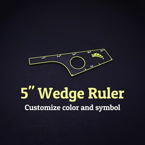 Op de afbeelding: Een zwarte wigliniaal met neongele randen en markeringen, voorzien van een cirkelvormige uitsparing en een grafisch symbool. De liniaal is gemarkeerd met cijfers van 1 tot 5 inch. De tekst 5" Wedge Ruler en Customize color and symbol is zichtbaar.