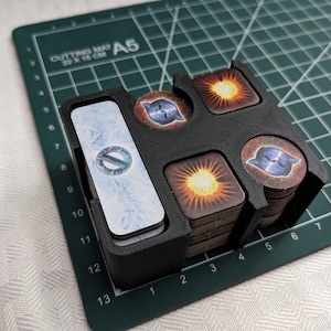 以下が含まれることがあります： ゲームカードを収納するための4つのスロットが付いた黒いプラスチック製のオーガナイザー。オーガナイザーには、側面に1枚のカードを収納するためのスロットがあります。カードはすべて異なる色で、さまざまなデザインが施されています。