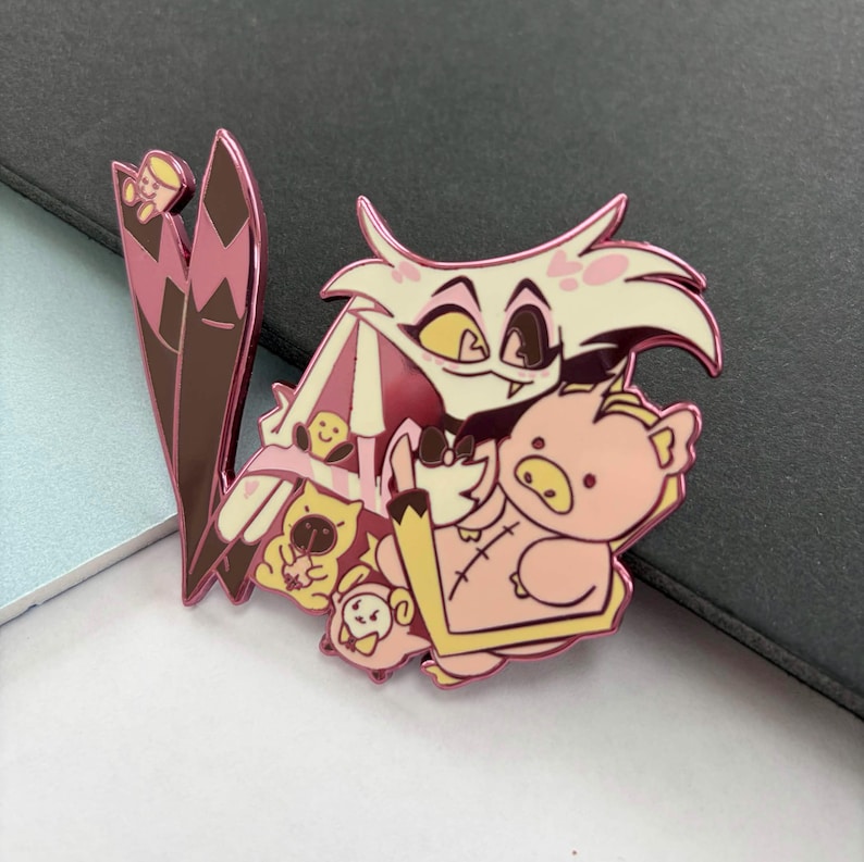 May include: A pink and white enamel pin featuring a cartoon character with a spider-like appearance, surrounded by several smaller cartoon characters. The pin has a glossy finish and a detailed design, perfect for fans of animation.