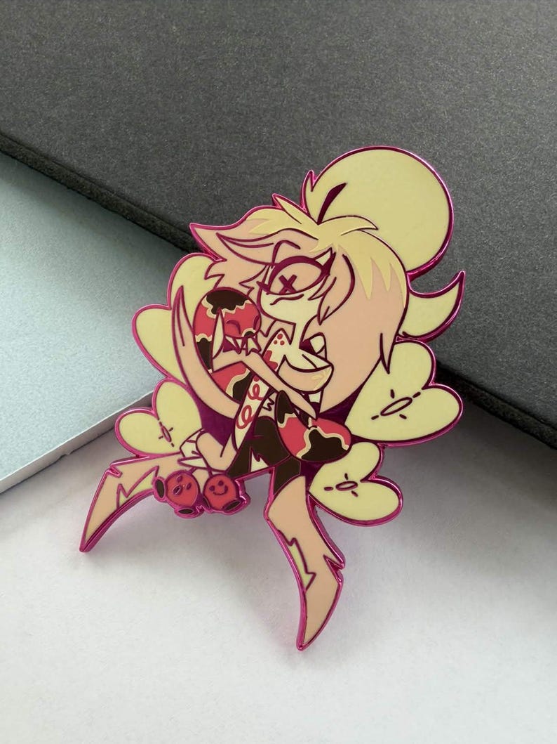 May include: A pin featuring a cartoon character with a yellow and pink color scheme. The character has a stylized design with multiple arms and a smiling expression. The pin has a pink outline and is likely made of metal.