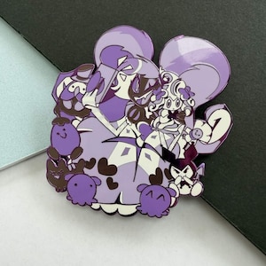 May include: A purple enamel pin featuring a cartoon illustration of several characters. The pin has a white border and a glossy finish. The characters are in shades of purple, brown, and white.