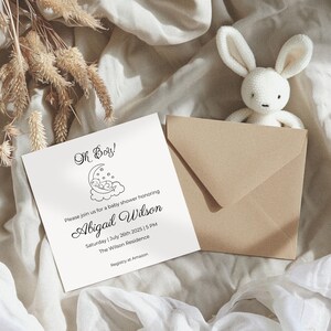 May include: A white card with black text announcing a baby shower for Abigail Wilson. The card features a simple illustration of a baby sleeping on a crescent moon. The text reads "Oh Boy!" and includes the date, time, and location of the shower. The text also includes the phrase "Registry at Amazon".