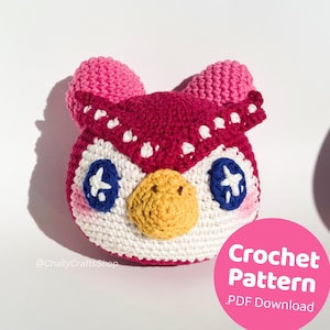 Puede incluir: Patrón de crochet para un amigurumi de búho rosa y blanco. El patrón está disponible para descargar en PDF. El búho tiene ojos azules con estrellas blancas y un pico amarillo.