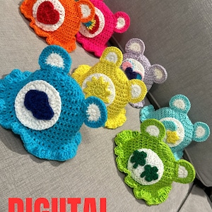 May include: A set of seven crocheted Care Bear hats in various colors, including orange, pink, purple, blue, yellow, green, and teal. Each hat features a unique Care Bear symbol, such as a heart, a star, a rainbow, a cloud, a flower, a clover, and a moon. The hats are arranged in a row on a gray couch. The text "DIGITAL PATTERN" is printed in red letters below the hats.