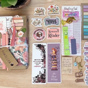 May include: A collection of book-themed items, including stickers, bookmarks, and a gift box. The stickers feature open books with floral designs, and the bookmarks have quotes and illustrations. The gift box is wrapped in floral paper and tied with a tassel.