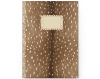 May include: A rectangular notebook featuring a brown and white spotted animal fur pattern. The cover includes a vertical decorative lace-like border on the left side and a central rectangular cream-coloured label with a scalloped edge for text.
