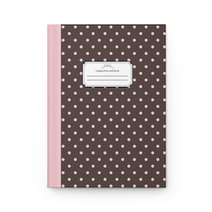 May include: A composition notebook with a dark brown cover featuring a repeating pattern of light pink polka dots. The center of the cover displays a white rectangular label with a small bow icon and the text composition notebook.