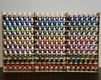 May include: A wooden paint rack with multiple shelves, holding rows of small bottles of paint in various colors. The bottles are arranged in a rainbow pattern, with the lightest colors at the top and the darkest colors at the bottom.