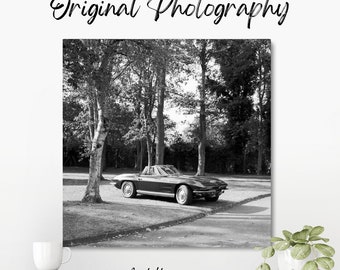 Original black and white photograph of a 1967 Chevrolet Corvette convertible parked at a car show in amongst trees at Bicester Heritage.