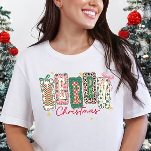 Camiseta navideña estilo preppy, camiseta navideña con letras en patchwork, camiseta navideña con lazo coqueto, camiseta navideña con estampado retro