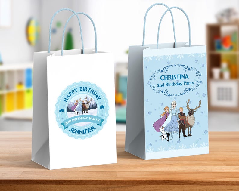May include: Two white gift bags with pale blue handles. One bag features a blue circular design with the text "Happy Birthday" and "Jennifer". The other bag has a pale blue background with the text "Christina 2nd Birthday Party".