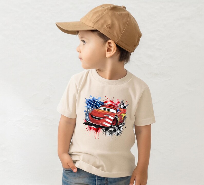 A young boy wearing a baseball cap and a t-shirt with a graphic of a red car and an American flag design.