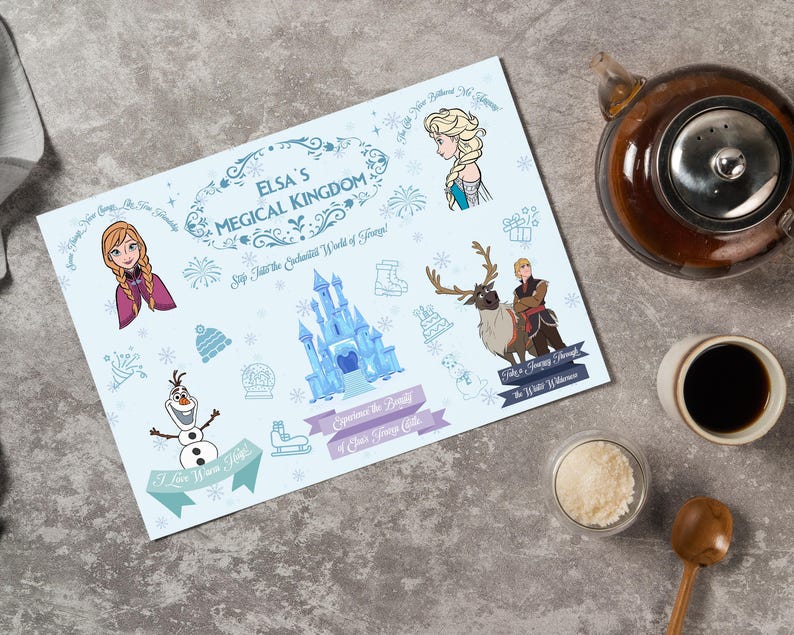 May include: A light blue placemat featuring Elsa's Magical Kingdom theme with illustrations of characters and elements from the movie. The placemat includes text and decorative borders, with a teapot, cup of coffee, and sugar bowl in the background.