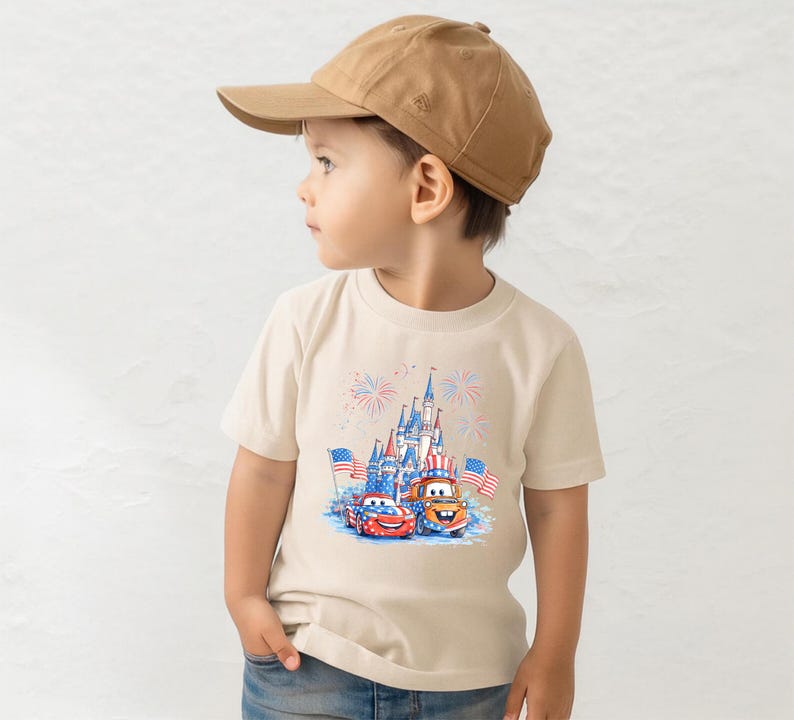 A young boy wearing a baseball cap and a t-shirt with a graphic of a castle and two cars, likely from the Disney Cars movie franchise.