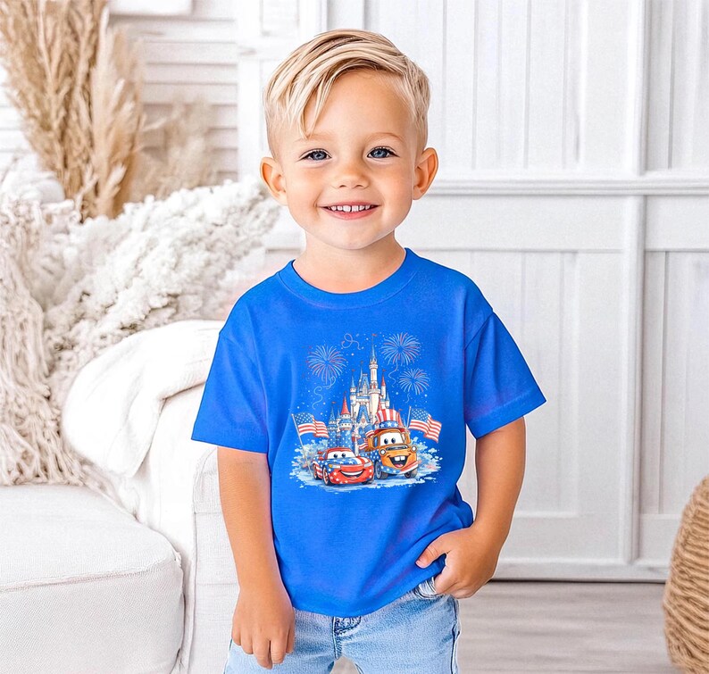 A young boy wearing a blue t-shirt with a Disney Cars graphic and a castle in the background, smiling at the camera.