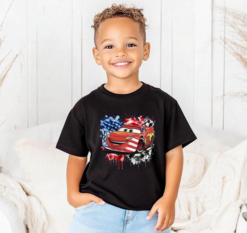 A young boy wearing a black t-shirt with a graphic of a red car and an American flag design.