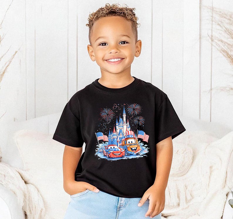 A young boy wearing a black t-shirt with a graphic of a castle and fireworks, smiling at the camera.