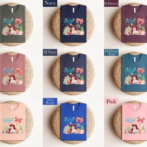 The image is a collage of nine t-shirts, each with a different color and design, displayed on a woven placemat.