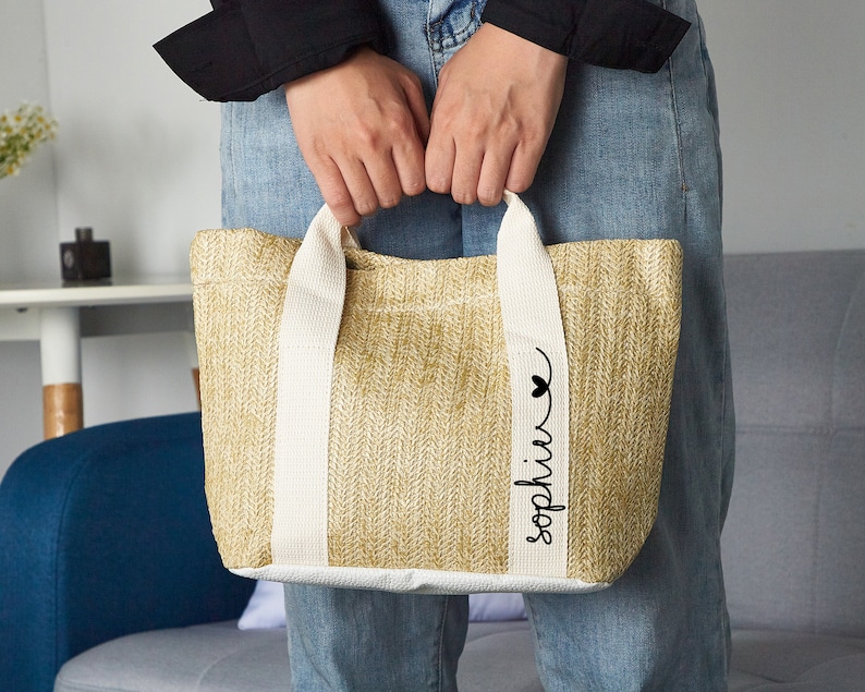 Puede incluir: Una bolsa de mano beige con asas blancas y un coraz&oacute;n negro y el nombre "Sophia" escrito en la parte delantera.