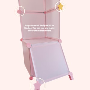 May include: A pink modular storage unit with a flexible peg connector system. The unit features star-shaped and round connectors. Text on the image reads: "Peg connector designed to be flexible. You can mix and match different shapes/colors."