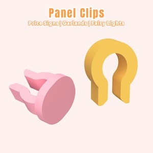 May include: Two panel clips in the image. One is pink and the other is yellow. The text at the top says "Panel Clips". Below the text are the words "Price Signs | Garlands | Fairy Lights".
